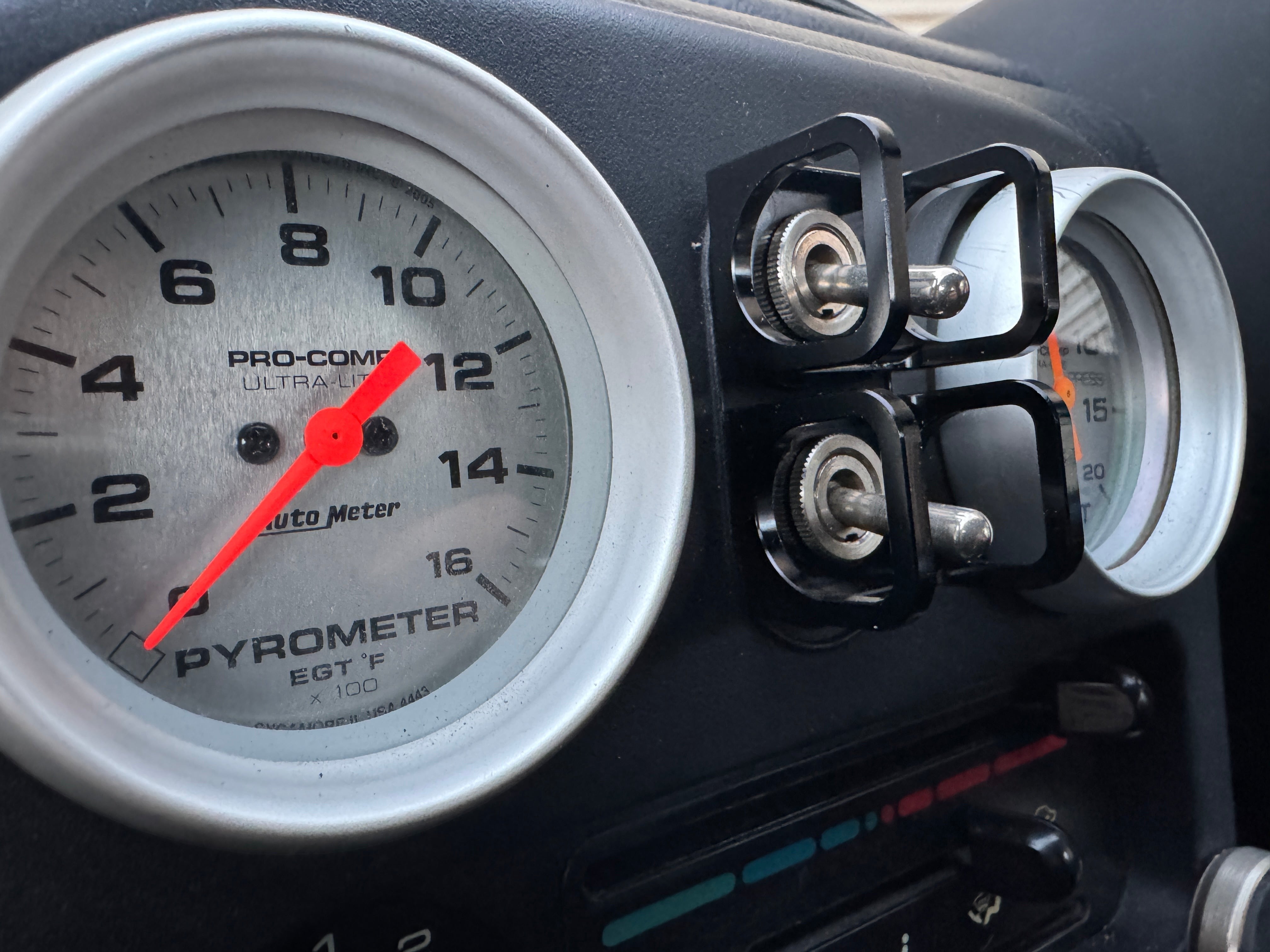 Duskie ISS-STYLE black anodized billet aluminum toggle switch guard protecting two switches next to gauges.