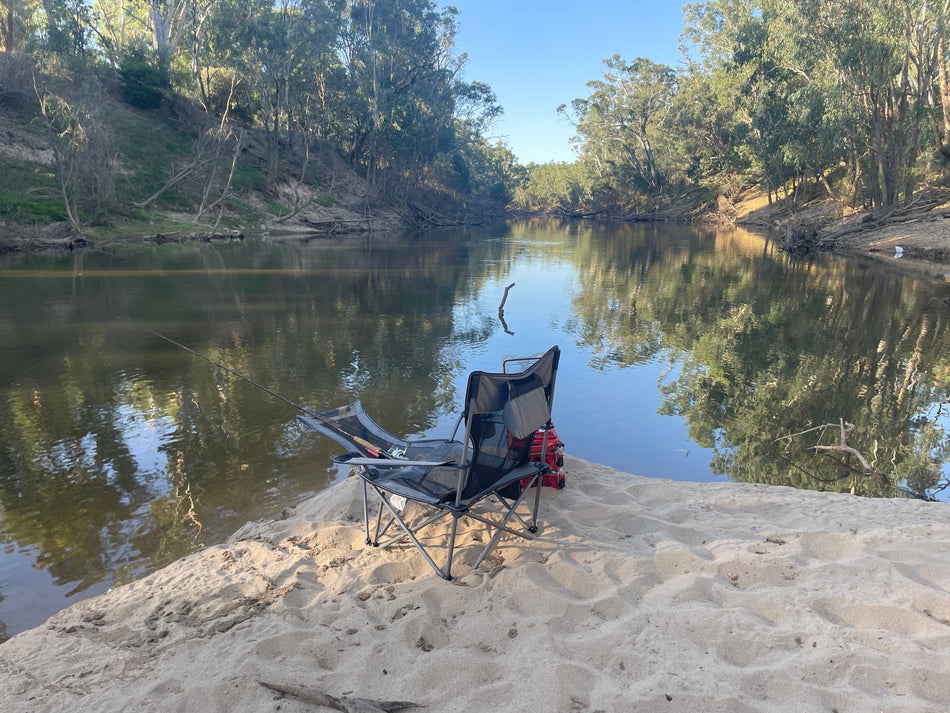 Duskie blue KEFOMOL portable reclining camping chair with footrest and mesh back set on a sandy riverbank.