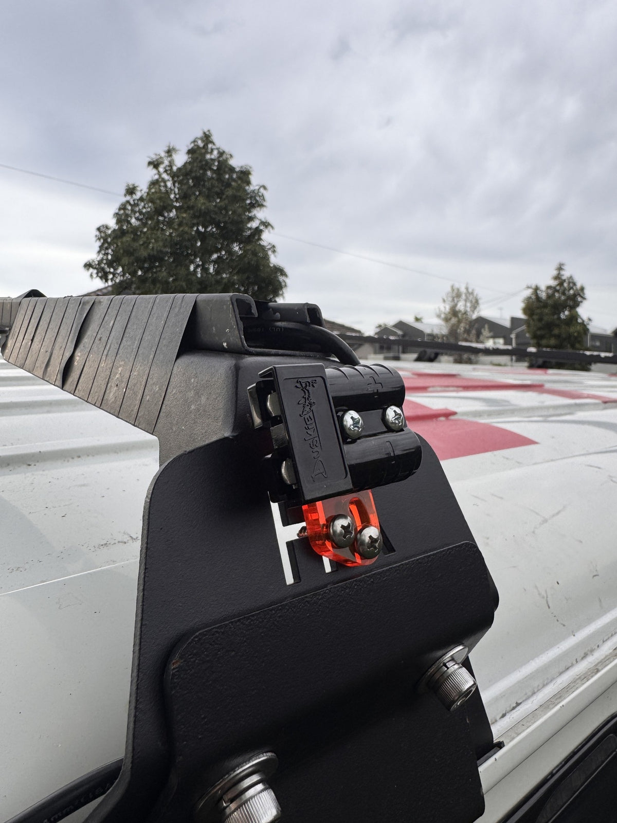 RICK 50A connector mounted on a roof rack bracket on a white van, with the orange acrylic bracket and stainless screws.